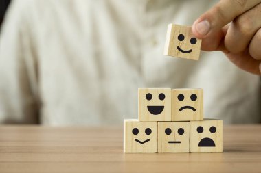 Müşteri anketinin hizmet derecelendirme geri bildirimi hakkında Happy 'nin küp bloklarına el ele tutuşmasını kapat. Yıllık iş tatmini araştırması konsepti. Birçok üzgün ya da mutlu insan tahta masada. Kopya alanı.