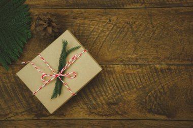 Mutlu Noel dekorasyonları ve Mutlu Yeni Yıl süslemeleri tablosu. Ev stüdyo masasındaki kırsal kahverengi ahşap arka planda köknar ağacı ve hediye kutusu temel nesneler yer almaktadır..