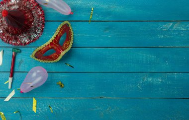 Masa üstü görüntü güzel renkli karnaval festivali arka planı. Düz nesne ev ofis masası stüdyosundaki modern mavi ahşap konfeti üzerinde çeşitli maske dekorasyonu konfetisi yatıyordu. Kopya alanı.
