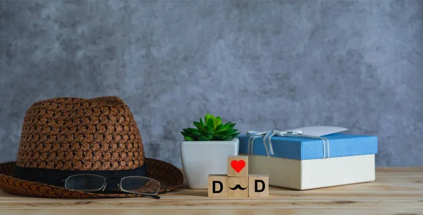 Objects on the table of Happy Fathers day holiday background concept.Word DAD with gift box and hat on grey backdrop.sign for celebration of festival daddy.mock up, border,banner, copy space