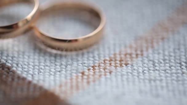 Dva svatební prsteny leží na pletené povrchu ubrus.
