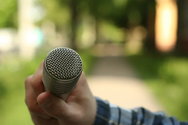 Hand hold microphone. Interview in the park. — Stock Photo, Image