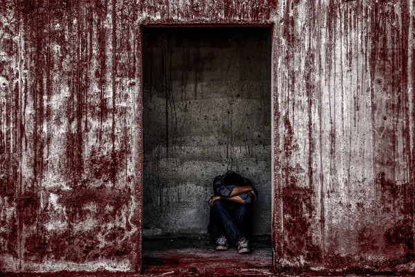 some people sitting in scary abandoned building with blood wall