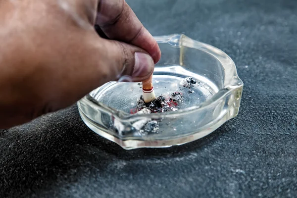 Mano con una colilla de cigarrillo tocado en medio de la ceniza, la gente fuma cigarrillo parece tratar de suicidarse, en el día "Día Mundial Sin Tabaco" por favor deje de fumar o deje de fumar para una buena salud . —  Fotos de Stock