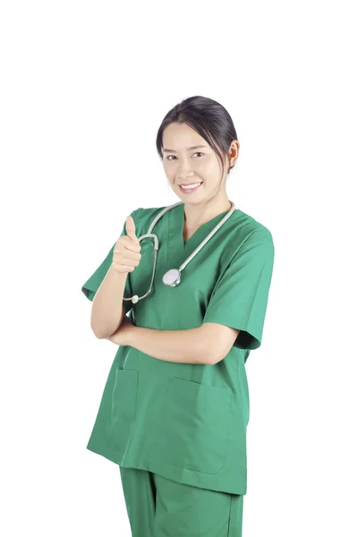 Smiling asian female doctor with stethoscope gesturing thumbs up isolated on white background — Stock Photo, Image