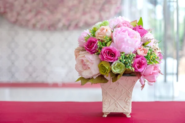 Fleurs artificielles colorées en tissu dans un vase rectangulaire en céramique sur une table — Photo