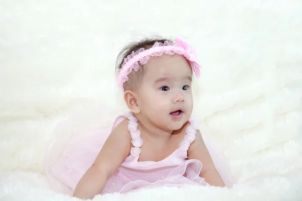 Aranyos öt hónap ázsiai baby rózsaszín ruha., fényes, puha szőnyegen nevetve. — Stock Fotó