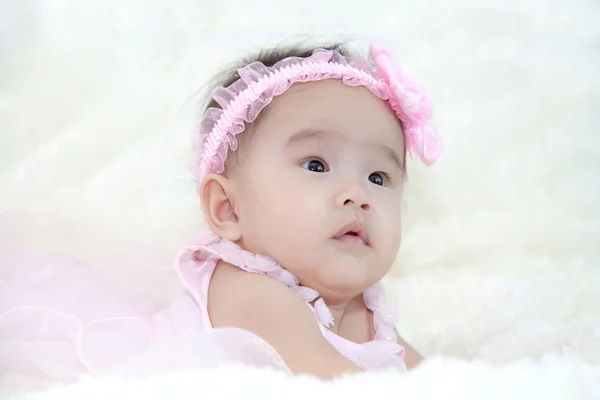 Cute five months asian baby in pink dress., on bright soft carpet. — Stock Photo, Image