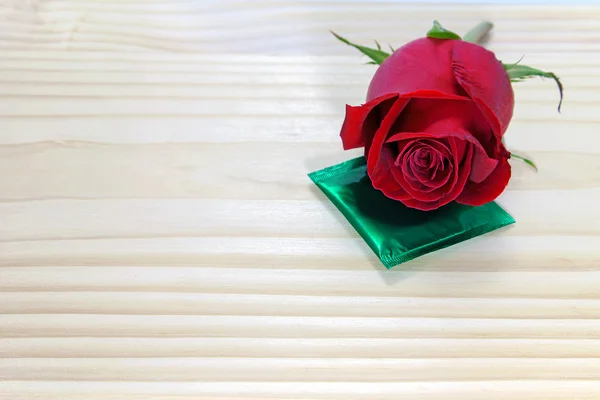 Rose rouge et préservatif sur table en bois, concept amour pour les valentines — Photo