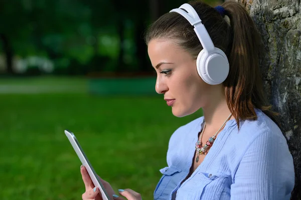 Girl in the park sitting and listening to music — Stock Photo, Image