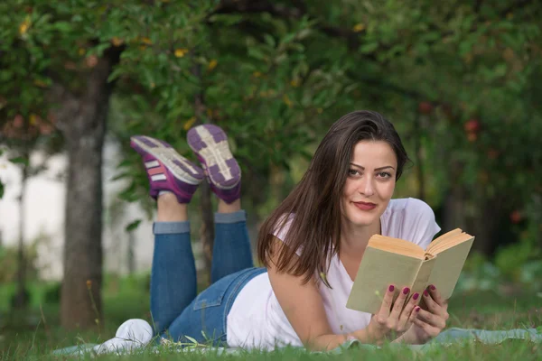 girl lies in the nature and reading a book