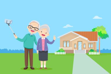 Yaşlı bir çift ve cep telefonunda selfie çubuğuyla fotoğraf çekiyorlar. Yaşlı bir adam ve kadın akıllı telefondan evlerinin önünde selfie çekiyorlar.