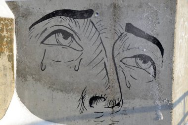 Beton duvar yüzeyinde ağlayan bir adamın resmi