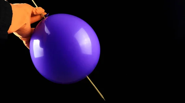 Bir el, bir balonu patlamadan şişle delme eylemini gösteriyor. Bilim konsepti balon kullanıyor.