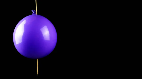 Bir el, bir balonu patlamadan şişle delme eylemini gösteriyor. Bilim konsepti balon kullanıyor.