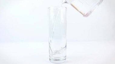 Beyaz bir zemin üzerinde cam bir fincana temiz su dökmek