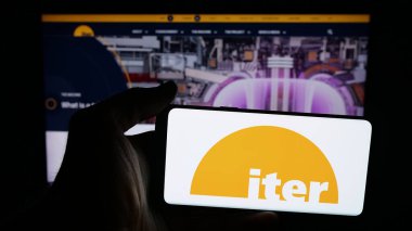 Stuttgart, Almanya - 10-06-2025: Nükleer füzyon güç reaktörü logosu olan cep telefonu sahibi kişi web sayfasının önünde ekranda. Telefon ekranına odaklan.