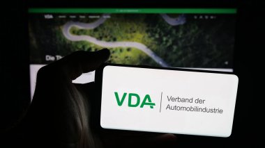 Stuttgart, Almanya - 10-06-2025: Web sayfası önünde üzerinde Almanca Verband der Automobidustrie (VDA) logosu bulunan cep telefonu sahibi kişi. Telefon ekranına odaklan.