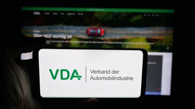 Stuttgart, Almanya - 10-06-2025: Web sayfası önünde üzerinde Almanca Verband der Automobidustrie (VDA) logosu bulunan kişi. Telefon ekranına odaklan.