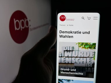 Stuttgart, Almanya - 10-08-2025: Logonun önünde Bundeszentrale kürk politikacısı Bildung 'un (bpb) web sayfası olan akıllı telefon sahibi kişi. Telefon ekranının merkezine odaklan.