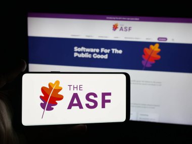 Stuttgart, Almanya - 10-08-2025: Web sitesi önünde üzerinde Apache Yazılım Vakfı (ASF) organizasyonu logosu bulunan akıllı telefon sahibi kişi. Telefon ekranına odaklan.