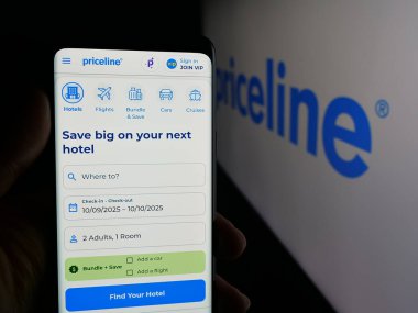 Stuttgart, Almanya - 10-09-2025: ABD 'li çevrimiçi seyahat şirketi Priceline.com LLLC' nin web sayfası ile logo önünde cep telefonu tutan kişi. Telefon ekranının merkezine odaklan.