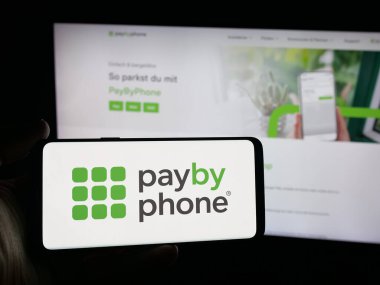 Stuttgart, Almanya - 10-09-2025: Kanadalı park uygulaması şirketi PayByPhone 'un logosunu elinde tutan kişi web sitesinin önünde ekranda. Telefon ekranına odaklan.
