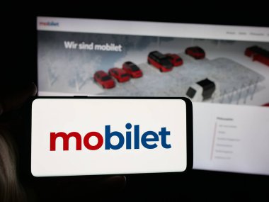 Stuttgart, Almanya - 10-09-2025: İnternet sitesinin önünde Alman mobil uygulama şirketi Mobilet 'in logosuna sahip akıllı telefon sahibi kişi. Telefon ekranına odaklan.