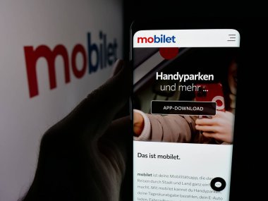 Stuttgart, Almanya - 10-09-2025: Alman mobil uygulama şirketi Mobilet 'in web sayfası olan akıllı telefon sahibi kişi logonun önünde ekranda. Telefon ekranının merkezine odaklan.