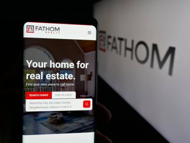 Stuttgart, Almanya - 10-09-2025: ABD 'li gayrimenkul şirketi Fathom Holding Inc.' nin web sayfası logo önünde ekranda. Telefon ekranının merkezine odaklan.