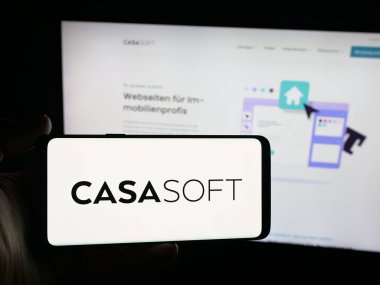 Stuttgart, Almanya - 10-09-2025: İsviçreli emlak yazılım şirketi Casasoft AG 'nin logosuna sahip akıllı telefonu web sitesinin önünde ekranda tutan kişi. Telefon ekranına odaklan.