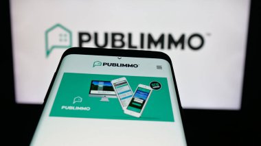 Stuttgart, Almanya - 10-09-2025: İsviçreli emlak yazılım şirketi Publimmo 'nun web sitesinin bulunduğu cep telefonu logonun önünde ekranda. Telefon ekranının sol üst kısmına odaklan.
