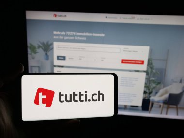 Stuttgart, Almanya - 10-09-2025: Üzerinde İsviçre sınıflandırması platform şirket tuttusu logosu olan akıllı telefon tutan kişi web sitesinin önünde ekranda. Telefon ekranına odaklan.