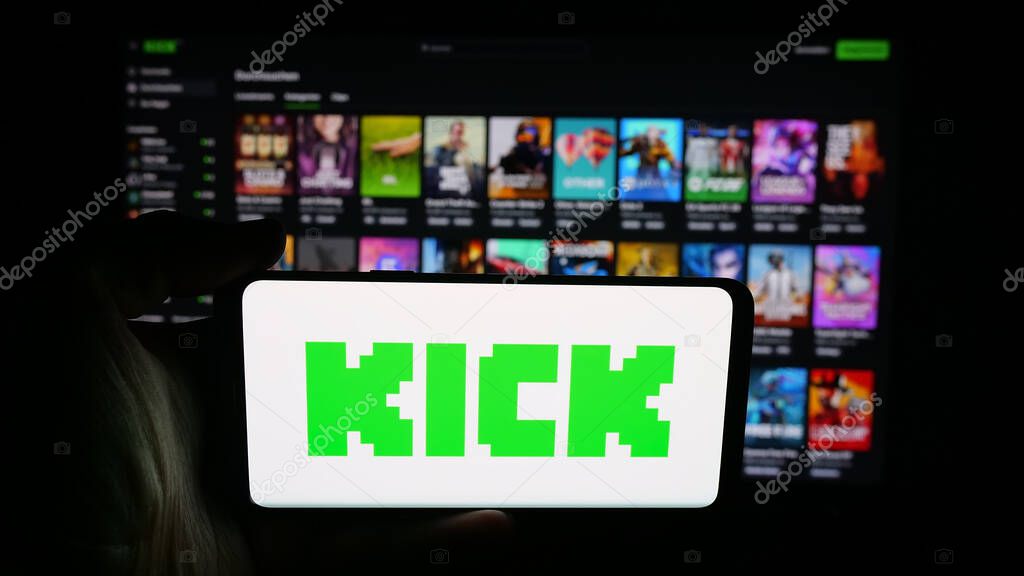 Stuttgart, Germany - 10-06-2025: Person holding cellphone with logo of video livestreaming platform company Kick.com on screen in front of webpage. Focus on phone display.