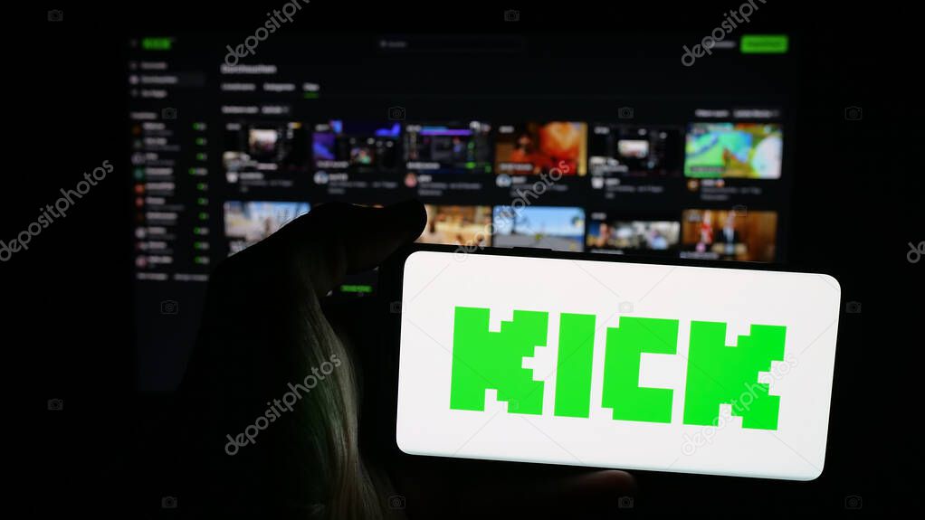 Stuttgart, Germany - 10-06-2025: Person holding mobile phone with logo of video livestreaming platform company Kick.com on screen in front of web page. Focus on phone display.