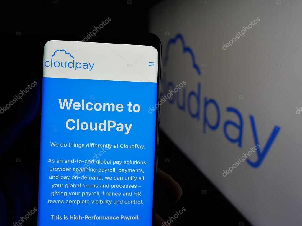 Stuttgart, Germany - 10-08-2025: Person holding cellphone with webpage of British payroll services company CloudPay Inc on screen in front of logo. Focus on center of phone display.