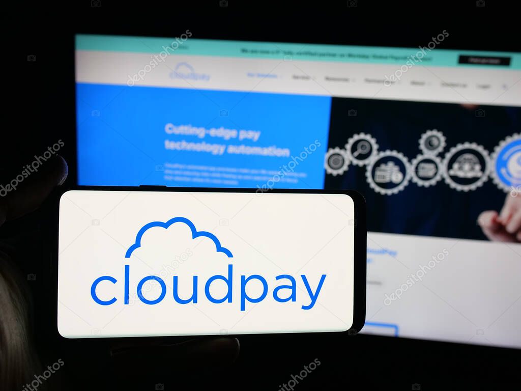 Stuttgart, Germany - 10-08-2025: Person holding smartphone with logo of British payroll services company CloudPay Inc on screen in front of website. Focus on phone display.