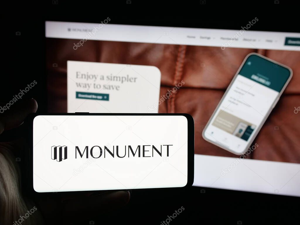 Stuttgart, Germany - 10-08-2025: Person holding smartphone with logo of British banking company Monument Bank Limited on screen in front of website. Focus on phone display.