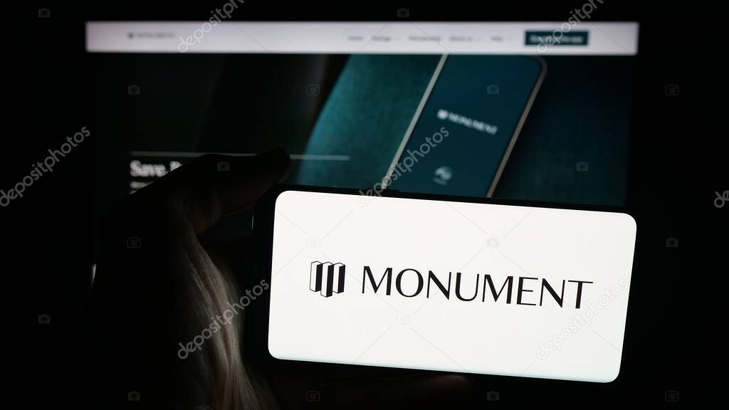 Stuttgart, Germany - 10-08-2025: Person holding mobile phone with logo of British banking company Monument Bank Limited on screen in front of web page. Focus on phone display.