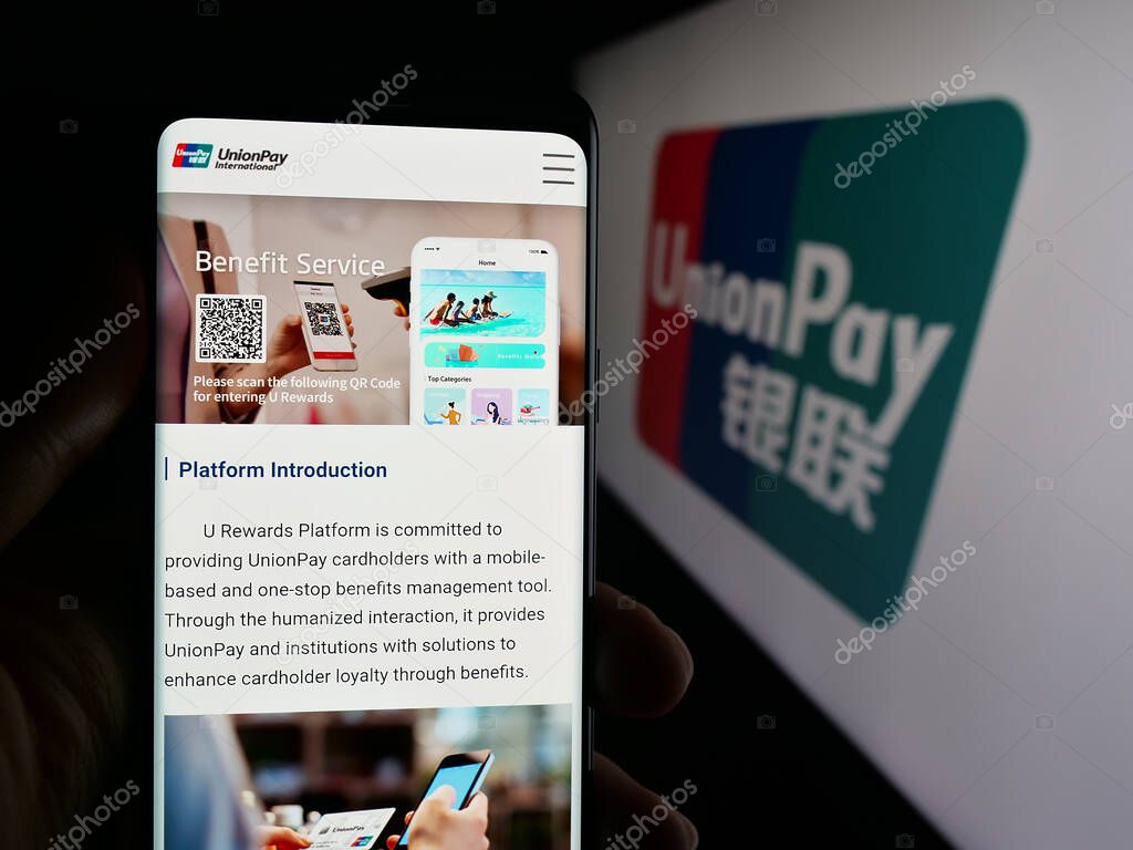 Stuttgart, Germany - 10-08-2025: Person holding cellphone with webpage of Chinese credit card company China UnionPay on screen in front of logo. Focus on center of phone display.