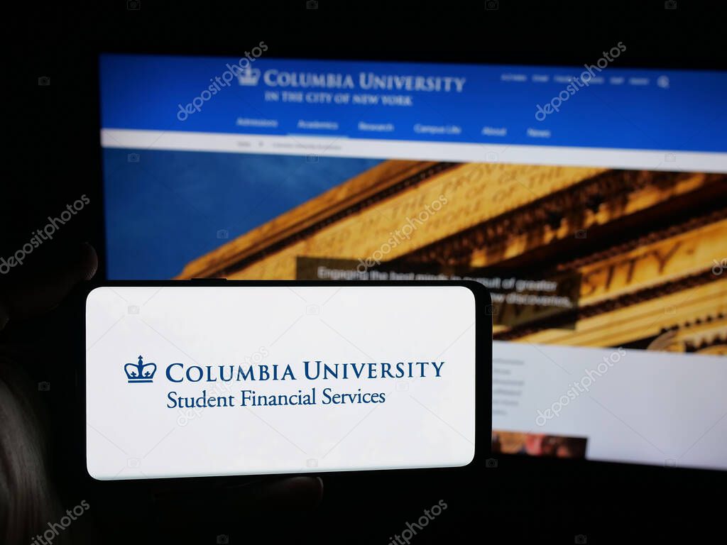 Stuttgart, Germany - 10-09-2025: Person holding smartphone with logo of Columbia University in the City of New York on screen in front of website. Focus on phone display.