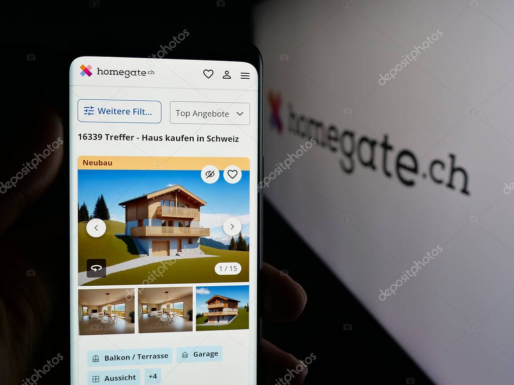 Stuttgart, Germany - 10-09-2025: Person holding smartphone with web page of Swiss real estate portal company Homegate on screen in front of logo. Focus on center of phone display.