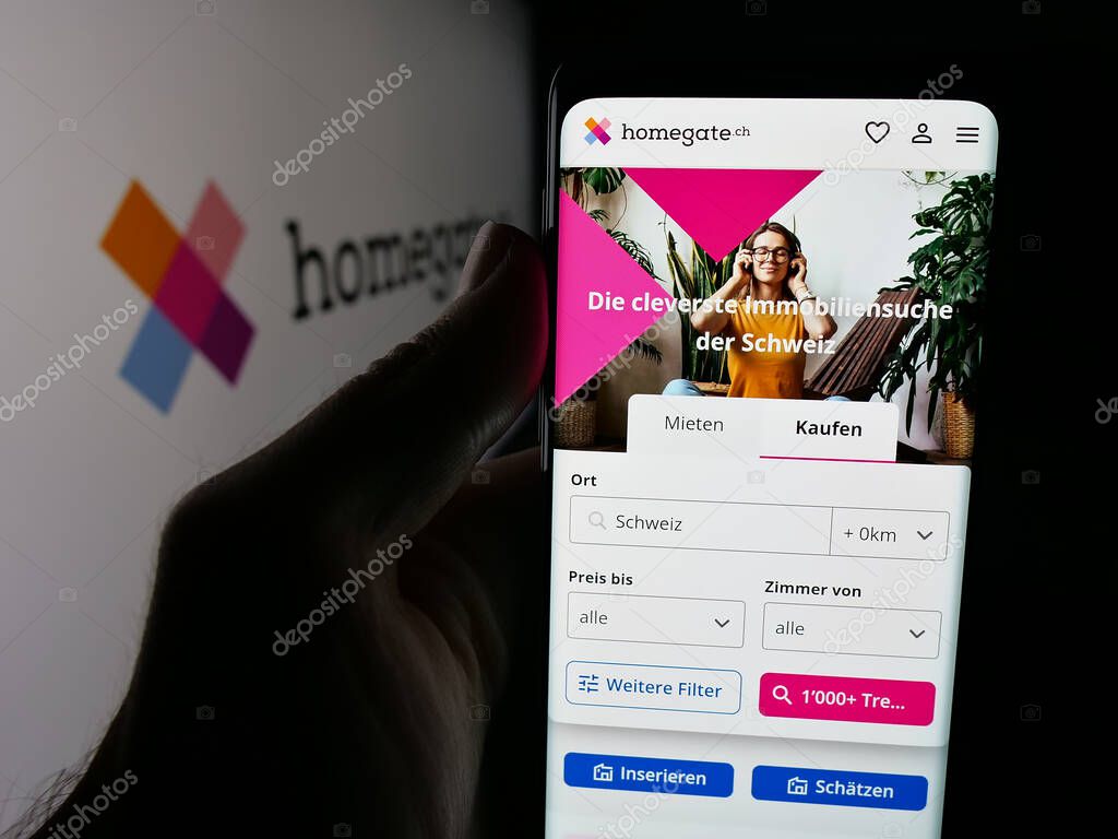 Stuttgart, Germany - 10-09-2025: Person holding cellphone with webpage of Swiss real estate portal company Homegate on screen in front of logo. Focus on center of phone display.