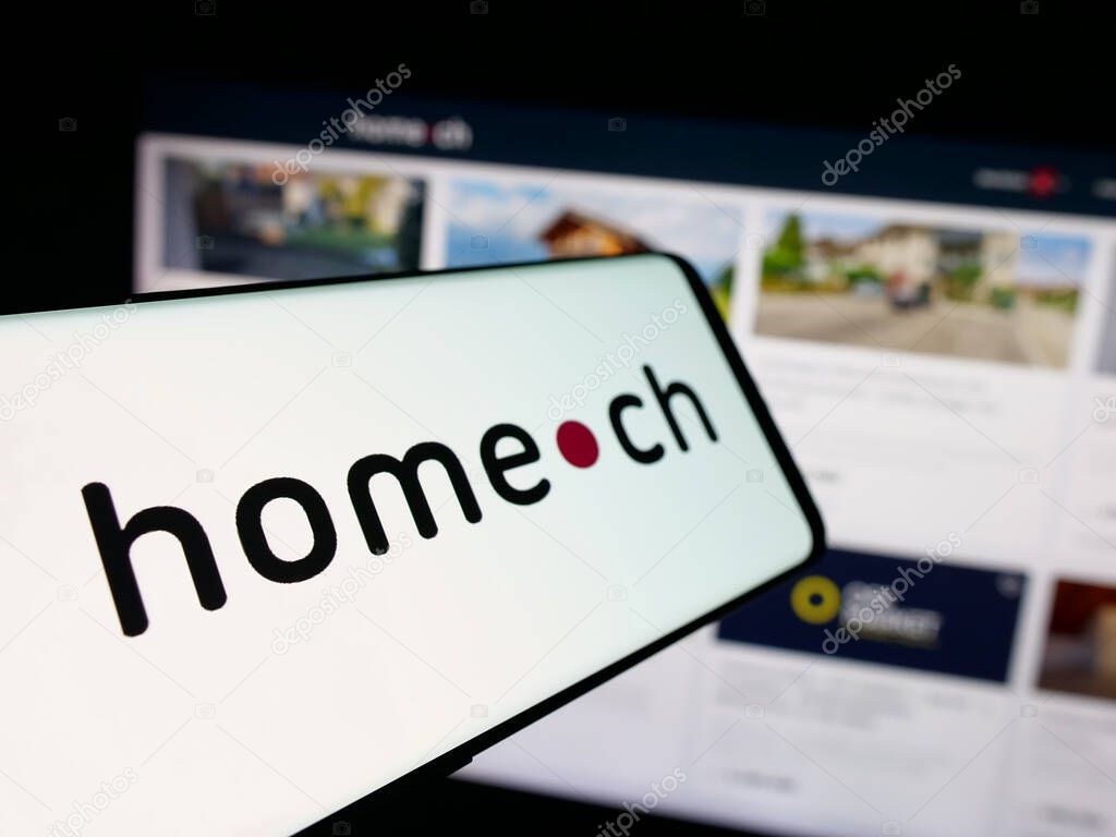 Stuttgart, Germany - 10-09-2025: Smartphone with logo of Swiss real estate portal company Home.ch on screen in front of website. Focus on center-left of phone display.