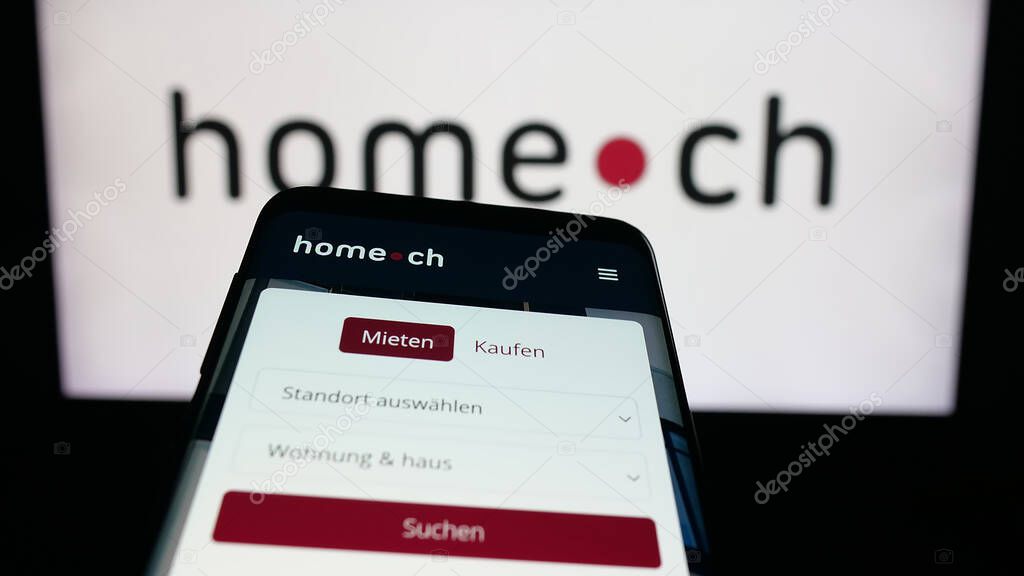Stuttgart, Germany - 10-09-2025: Mobile phone with website of Swiss real estate portal company Home.ch on screen in front of logo. Focus on top-left of phone display.