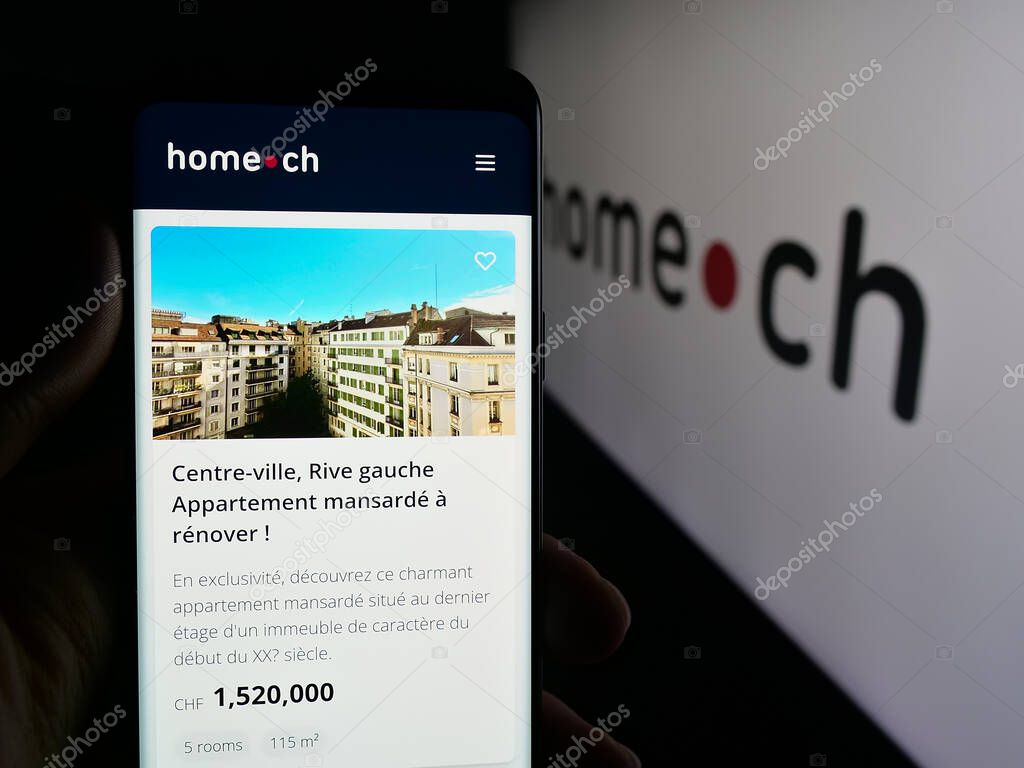 Stuttgart, Germany - 10-09-2025: Person holding cellphone with webpage of Swiss real estate portal company Home.ch on screen in front of logo. Focus on center of phone display.