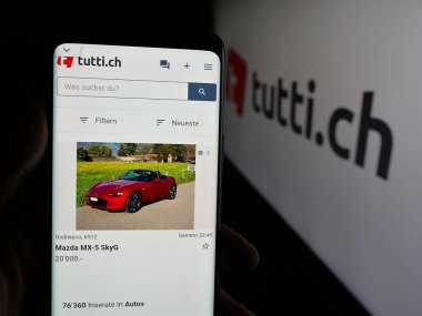 Stuttgart, Almanya - 10-09-2025: İsviçre 'de sınıflandırılan platform şirket tuttusunun web sayfası ile cep telefonu tutan kişi logonun önünde ekranda. Telefon ekranının merkezine odaklan.