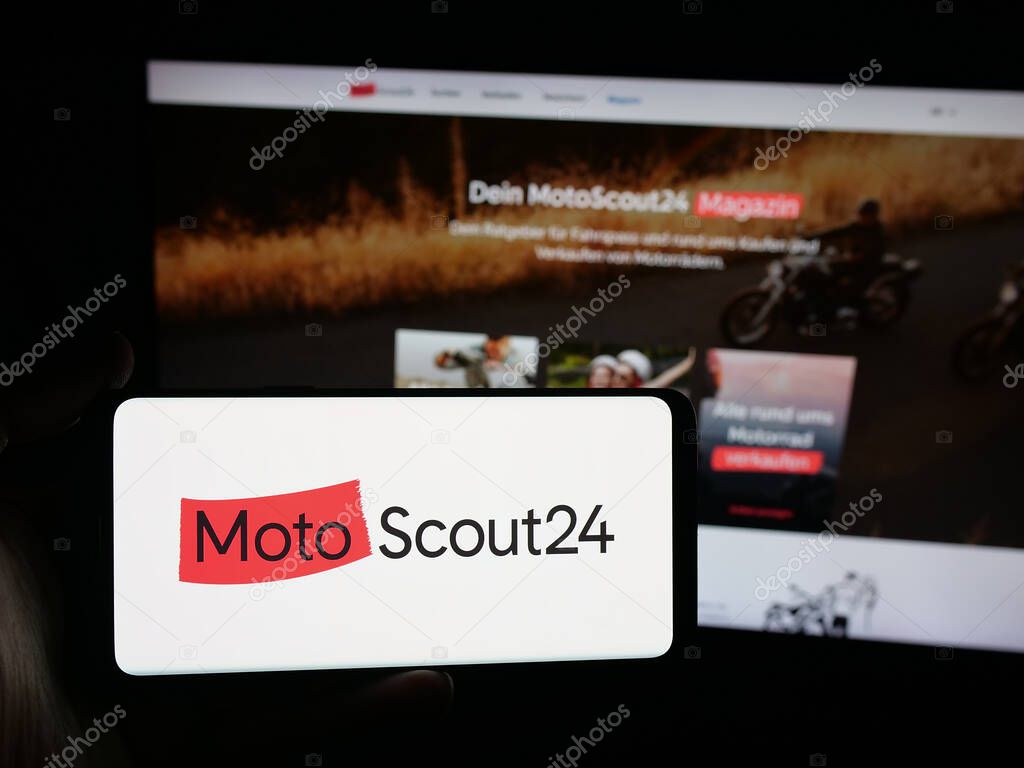 Stuttgart, Germany - 10-09-2025: Person holding smartphone with logo of motorcycle marketplace company MotoScout24 on screen in front of website. Focus on phone display.