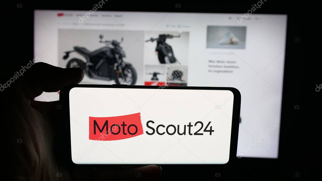 Stuttgart, Germany - 10-09-2025: Person holding cellphone with logo of motorcycle marketplace company MotoScout24 on screen in front of webpage. Focus on phone display.