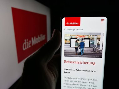 Stuttgart, Almanya - 10-10-2025: İsviçreli sigorta şirketi Mobiliar 'ın web sayfası olan akıllı telefon sahibi kişi logonun önünde ekranda. Telefon ekranının merkezine odaklan.